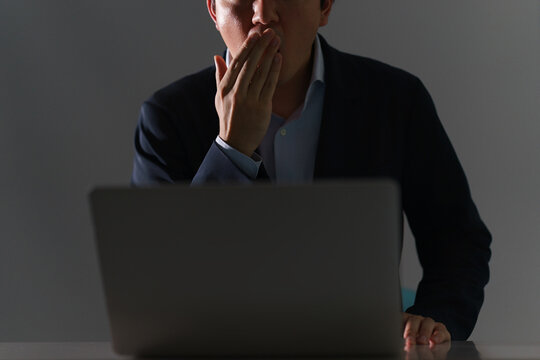 パソコンでショックなニュースを目にし口元を押さえて動揺する顔無しの30代のスーツ姿の男性