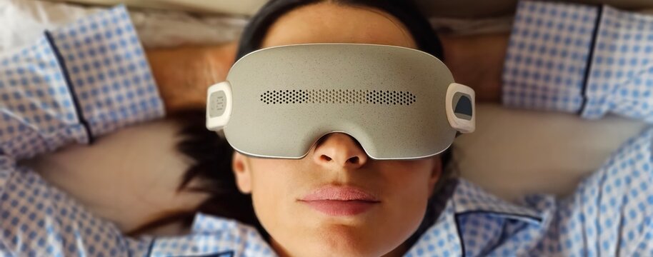 Woman with eye massage device lying on sofa. Improvement of vision and skin condition