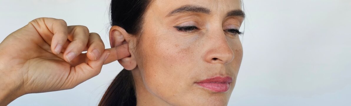 Woman scratching inside of ear with finger
