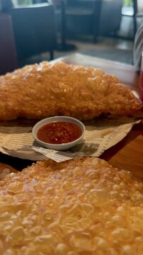 Appetizing hot cheburek served with traditional tarkhun and mors drinks. Crispy fried meat pastry with green tarragon soda and red berry beverage on table. Authentic street food concept.