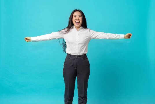 Excited Asian Businesswoman Jumping and Celebrating Victory on Blue Background
