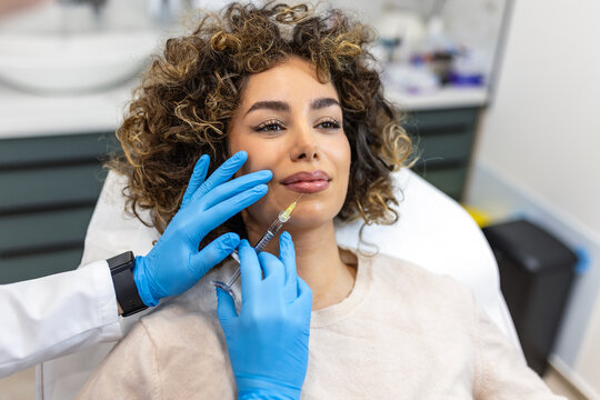 Lip filler injection. Professional aesthetician in blue gloves performing beauty procedure on attractive woman. Cosmetic treatment and plastic surgery concept. Lips augmentation in dermatology clinic.