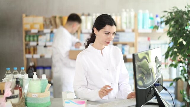 Young female pharmacist working with computer in pharmacy 