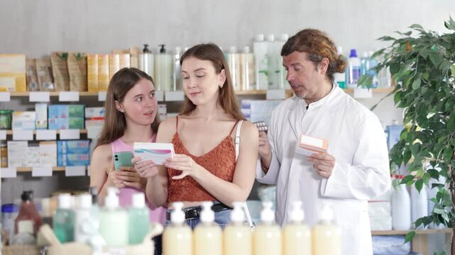 Mom with girl child buyer select tablet medicine, reads composition, finds out expired date information. Medicines for treatment and prevention. Man pharmacist offer help and consultation