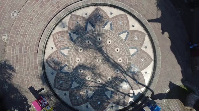 Toma a&eacute;rea de dron ascendiendo en rotaci&oacute;n con vista cenital revelando c&iacute;rculo de mandala colorido en las letras de Tlaquepaque Jalisco M&eacute;xico, patr&oacute;n geom&eacute;trico sim&eacute;trico con atractivo tur&iacute;stico