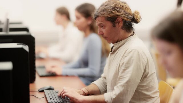 Man student of computer courses types on keyboard, performs work, educational practical task. Pupil performs educational tasks using computer