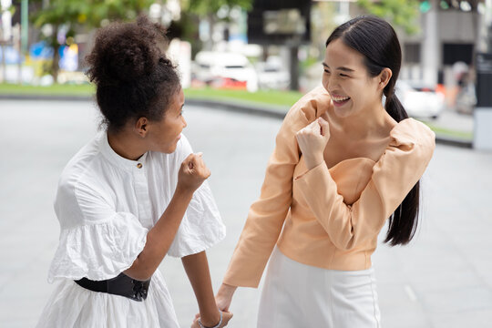 Two young adult women, Asian and African friends talking and having a good positive feeling together