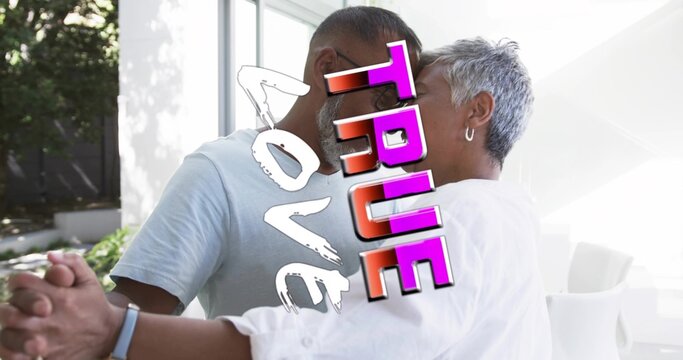 Touching heads, white-shirt, gray-tee couple holding hands by glass doors at home, TRUE LOVE sign