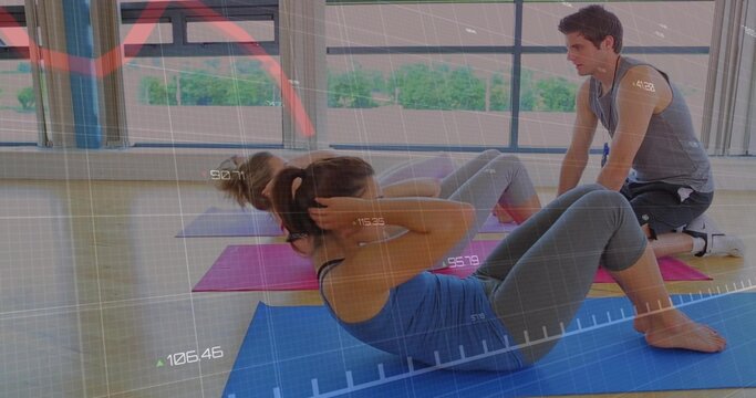 Doing abdominal crunches woman in workout gear on blue mat training with coach near windows