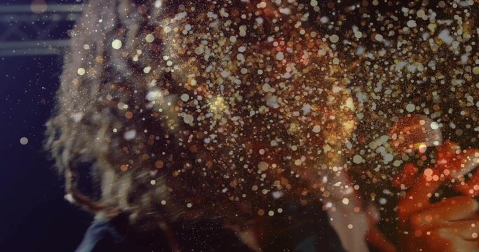 Singing backlit curly hair performer holding microphone on stage in dark clothing, bokeh sparkling