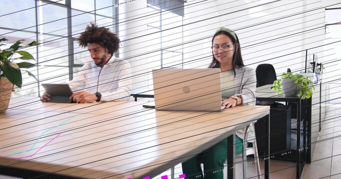 Working Middle Eastern man and Chinese woman in business clothes using tablet and laptop at table