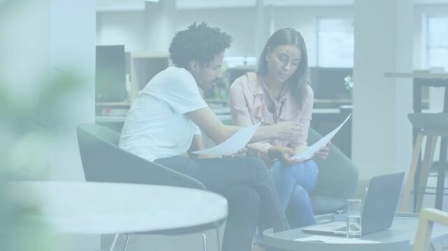 Pair comparing docs in lounge, man pointing, woman following, consulting laptop for business