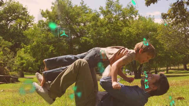 Man lifting child with legs, rocking airplane-to-lean for bonding while green tech holograms drift