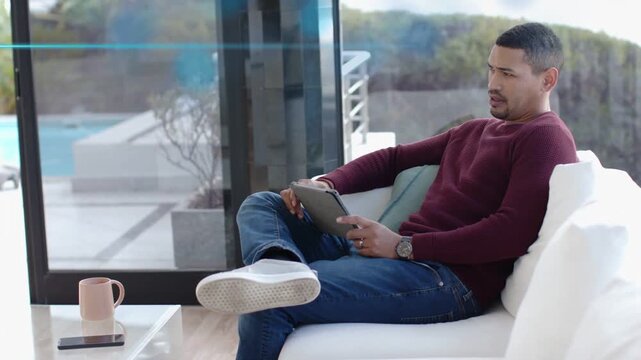 Man tapping tablet and causing blue overlay, reviewing tech dashboard while glancing patio view