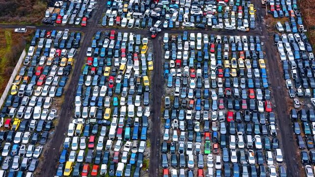 Car recycling facility. Straight down aerial view of wrecked cars separated by dirt paths in an industrial salvage yard.