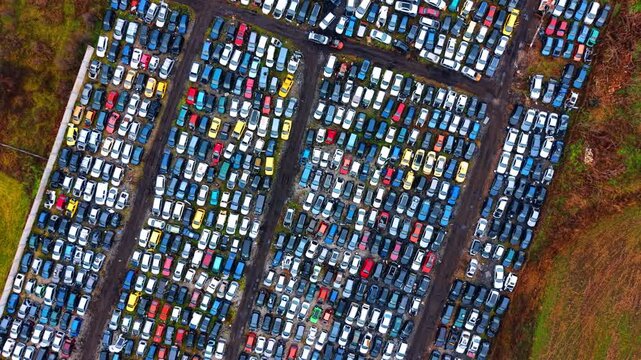 Systematic top down view of automotive salvage lot. Aerial grid pattern of scrapped vehicles arranged for dismantling and recycling at a junkyard.