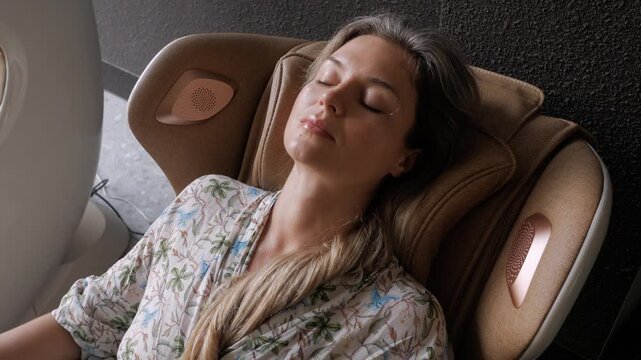 Woman relaxing with eyes closed in luxury massage chair at modern wellness lounge