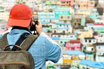 Naklejka premium Tourist in an orange cap takes a photo of the Gamcheon Cultural Village in South Korea.