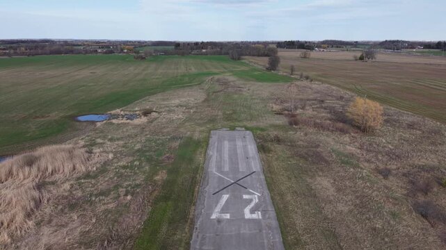Aerial drone shot pulling back from the "X" and "27" markings on a decommissioned runway, revealing the abandoned Toronto Markham Airport in Ontario