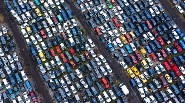 Aerial top view of colorful cars in a junkyard. High angle drone shot of rows of scrap cars at an outdoor salvage yard during daylight.