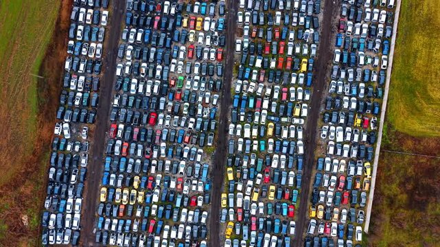 Aerial panorama of large scale car recycling lot. Overview of a massive outdoor lot containing hundreds of scrap vehicles organized by rows and sections.