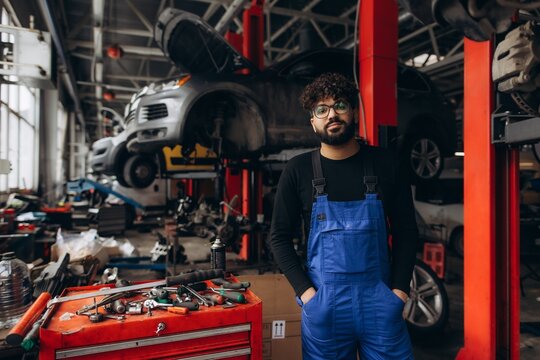 Mechanic in blue overalls standing in car workshop