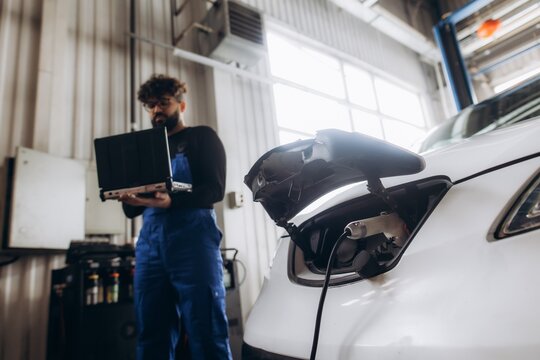 Mechanic diagnosing electric car charging at workshop