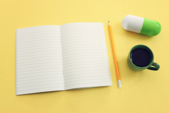 Colorful pill capsule toy on yellow background and empty notebook
