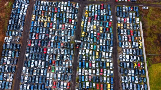 Overhead shot of organized vehicle recycling and scrap lot. Direct top-down view showing systematic arrangement of old cars at an automotive recycling and disposal center.