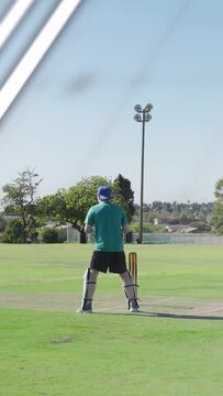 Vertical video: Batsman adjusting sports pitch for shot while bowler bowling overlays hiding stumps