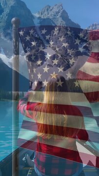 Vertical video: Woman rowing on mt lake reaching transparent US flag overlaying frame for travel