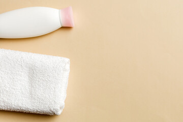 Obraz premium Cosmetic shampoo bottle mockup with towels on a colored table. Bathroom background, toilet accessories for hand and body care