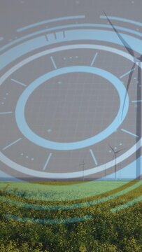 Vertical video: With wind rising blue HUD overlay pulsing turbines spinning slowly monitoring crops