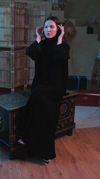 Young woman in black national Arab abaya clothes posing in atelier studio
