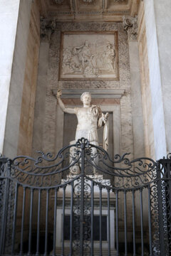 Statua monumentale di imperatore romano in armatura classica, scultura in marmo bianco con dettagli della lorica e mantello, simbolo dell'Impero Romano e del potere antico