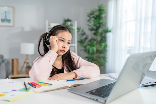 Asian young stressed kid learning online class with teacher at home. 