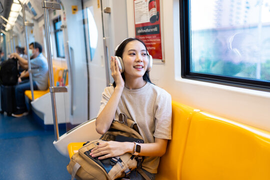 Asian young woman sitting on subway train seat while traveling in city. 