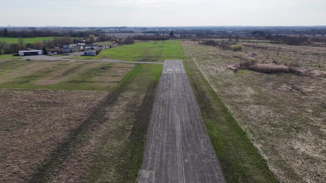Drone shot flying forward and tilting down over the weathered asphalt of runway 09 at the abandoned Toronto Markham Airport (CNU8) in Ontario