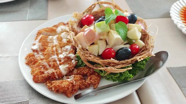 Fruit salad served in a crispy taro leaf cup with fried chicken.