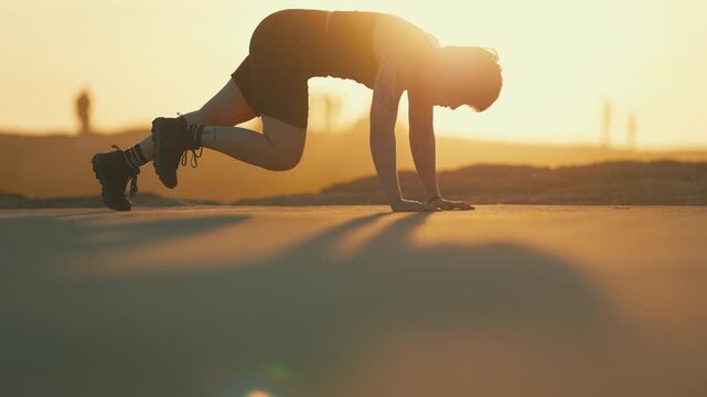 Silhouette of a woman doing push-ups at sunset