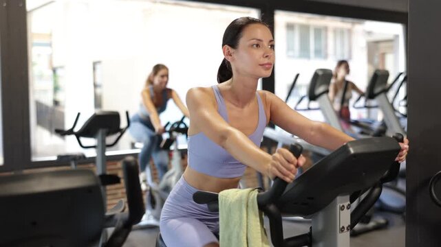 Woman in sportswear doing a workout on an exercise bike in the gym. European woman bought a fitness subscription for an athletic body