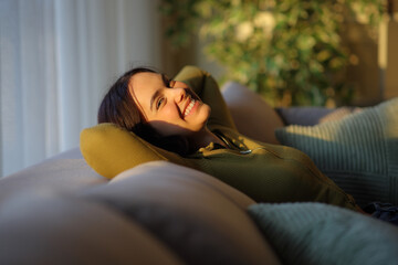 Fototapeta premium Happy woman relaxing at sunset at home looking at you