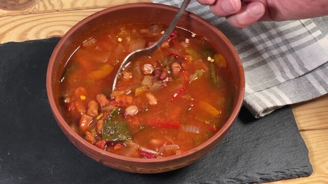 Stirring red bean soup with spinach and sausages in bowl