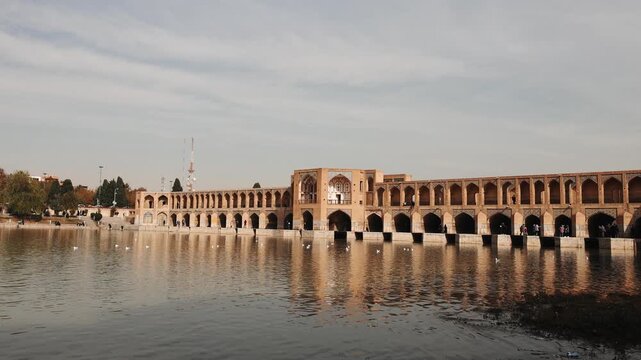 Khaju Bridge in Isfahan, Iran, reflected in the calm waters of the Zayandeh River. Scenic view of the historic 17th century Persian bridge with traditional arches and stone architecture