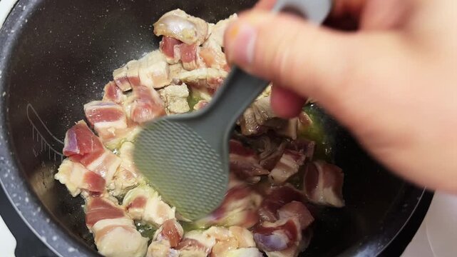 Stirring with spatula meat in multi-cooker for borscht cooking