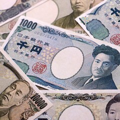 Japanese yen money bills pile on table. Japan banknotes of JPY currency close up. © Larysa