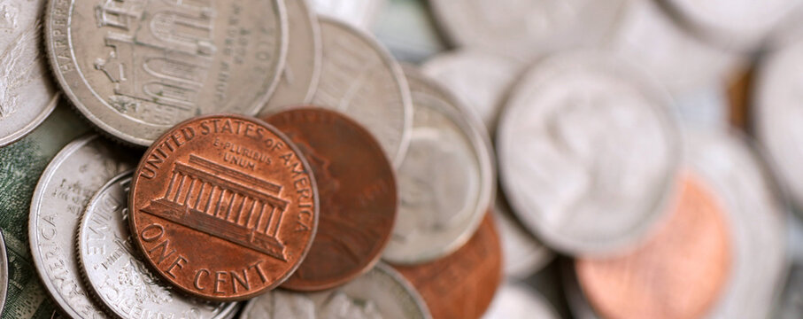 Big amount of United States coins on hundred dollar money bills arranged in chaotic order