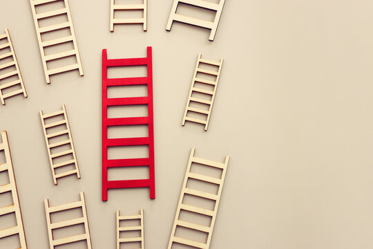 Red ladder among group of smaller ones. Concept of aiming high and achieving success
