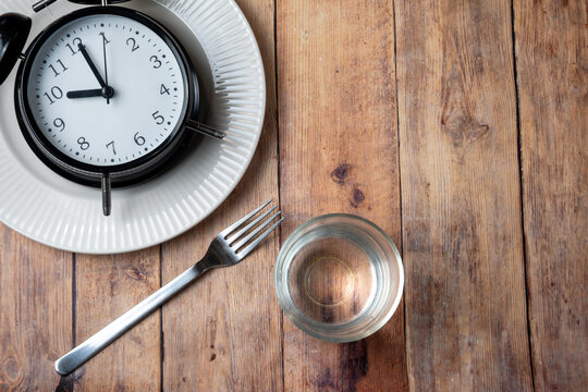 Fasting concept with empty plate water and clock