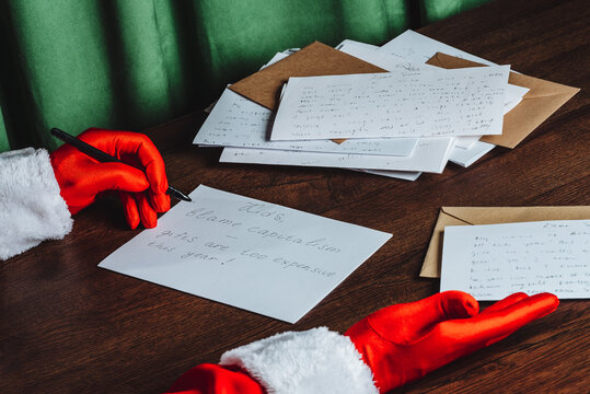 Santa Claus writing humorous Christmas letter about capitalism at desk